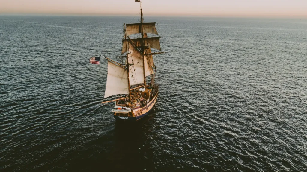 Historic tall ship sailing across the ocean, representing dogs on the Mayflower and the voyage to colonial America.